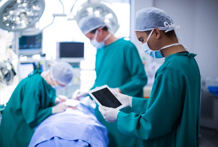 Surgeon using digital tablet in operation theater of hospital